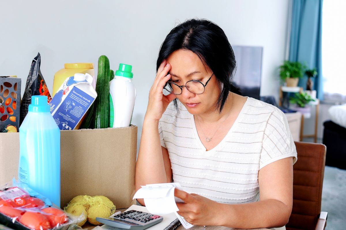 Woman Looking At Grocery Receipt Thinking About More Mindful Spending